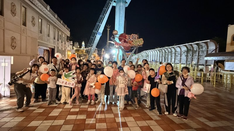 two men sitting on the grass looking at a laptop